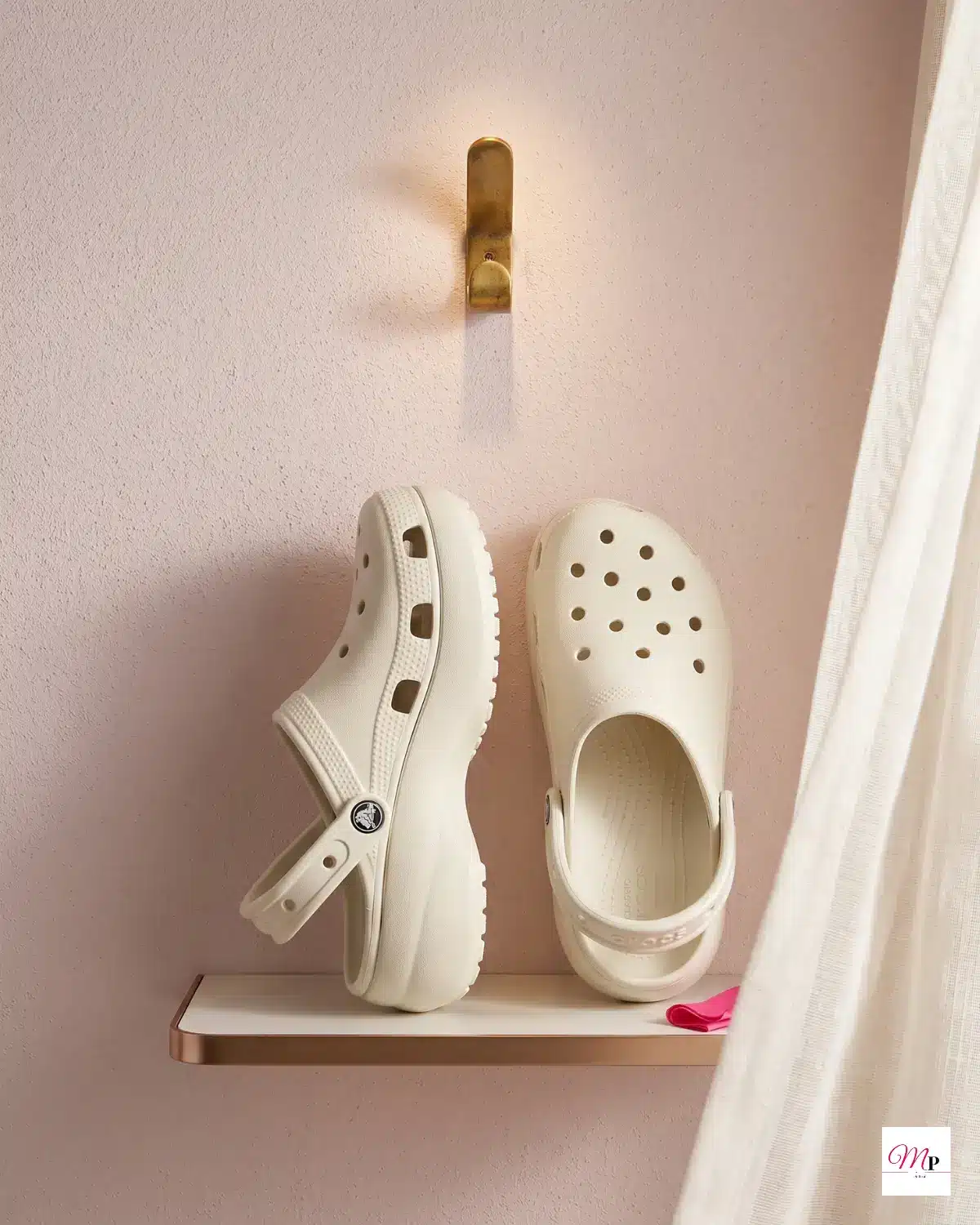 Crocs platform clogs mounted on wall shelf against blush pink wall showing ventilation holes and platform thickness — summer clogs India