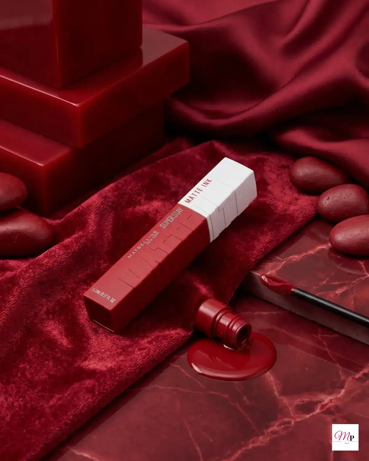Maybelline SuperStay Enchanter 380 deep berry red lipstick on crushed velvet with product spill
