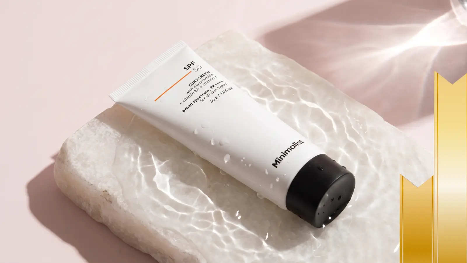 Minimalist SPF 50 sunscreen tube on wet stone slab with water droplets, broad spectrum PA++++ with niacinamide