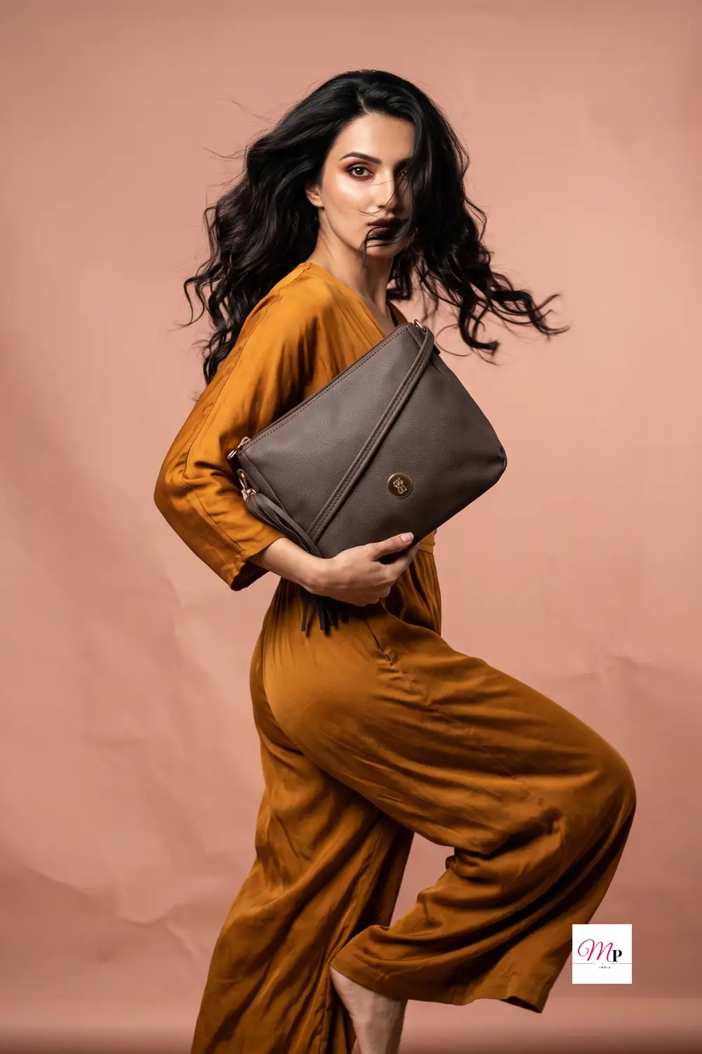 Editorial fashion shot of woman in mustard outfit holding Baggit clutch-style bag — Indian festive styling idea for sling bags, perfect for shaadi season