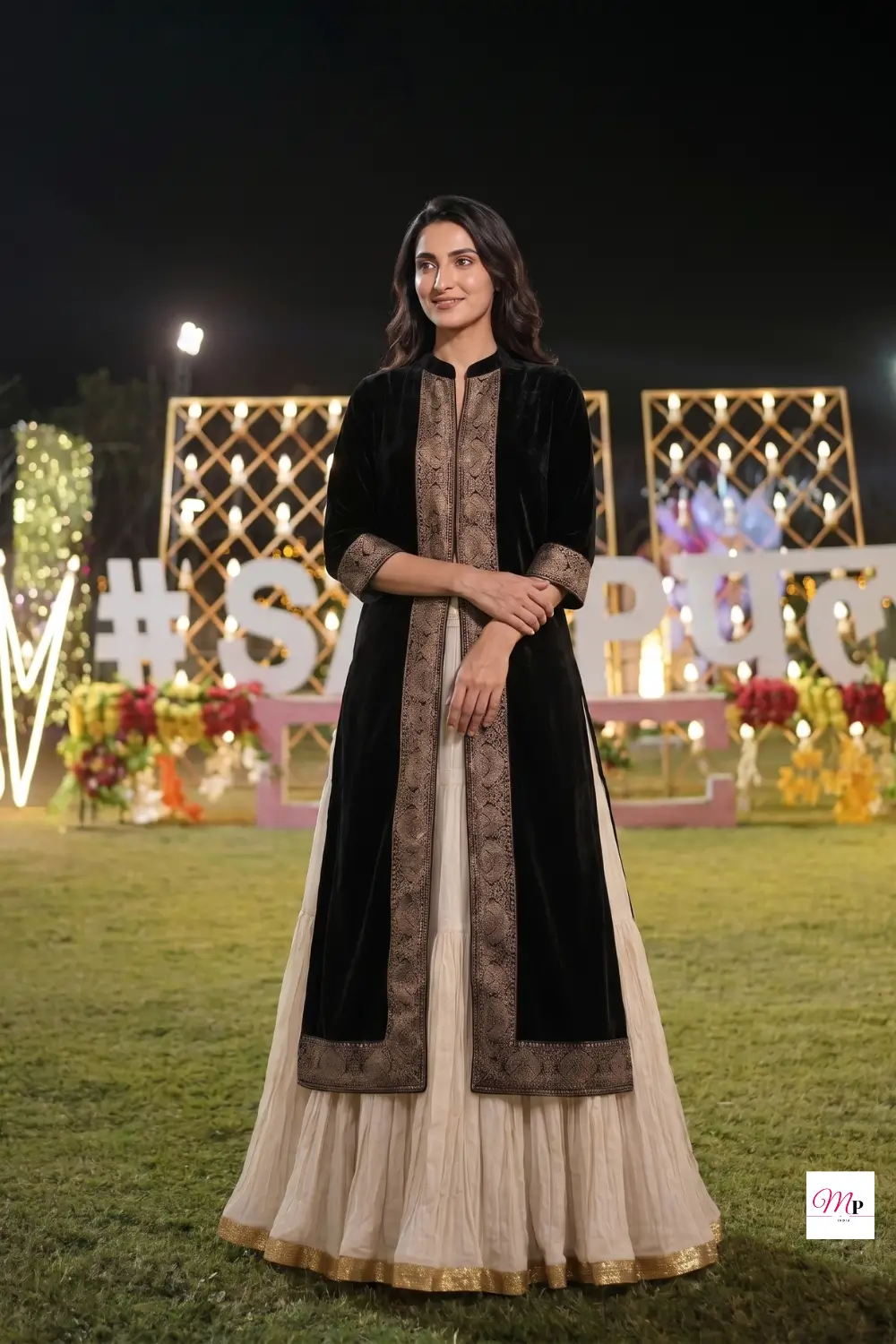 Black velvet anarkali kurta with gold embroidery styled for Indian wedding reception under decorative lights