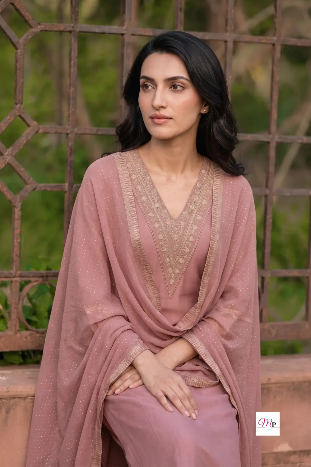 Model seated wearing dusty rose wedding guest kurta set with dupatta draped over shoulder, Gerua by Libas
