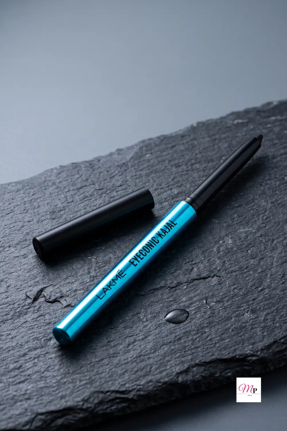 Lakme Eyeconic Kajal pencil tip close-up on dark slate surface with water droplet showing waterproof texture
