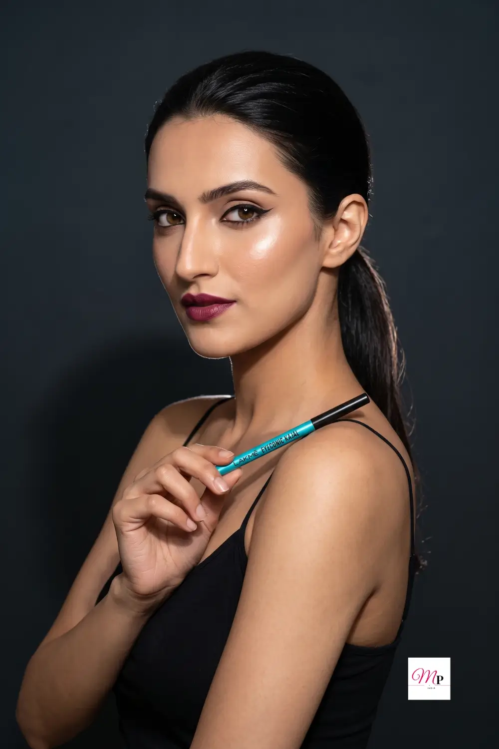 Model holding Lakme Eyeconic Kajal pencil against dark studio background