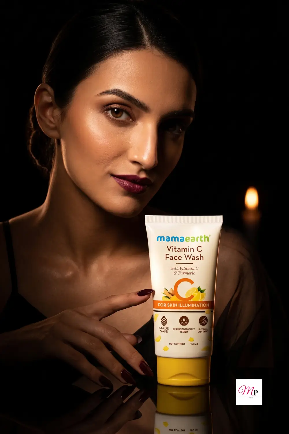 Woman holding Mamaearth Vitamin C Face Wash tube in dramatic warm studio lighting with candlelit background