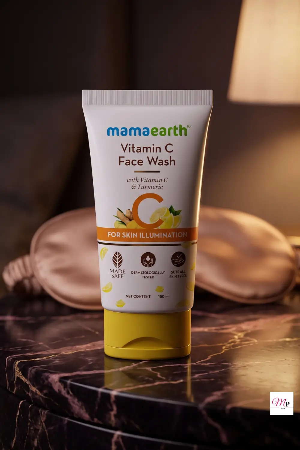 Mamaearth Vitamin C Face Wash tube on dark marble vanity with silk eye mask and warm bedside lamp