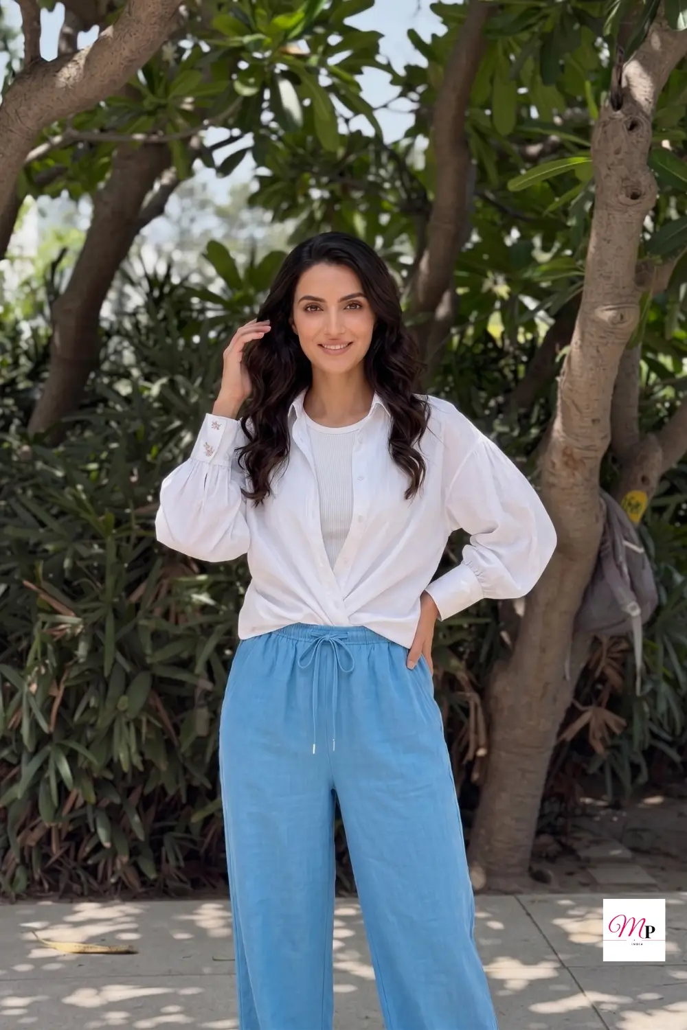 Sky blue linen viscose wide leg trousers for women styled with white shirt in garden setting