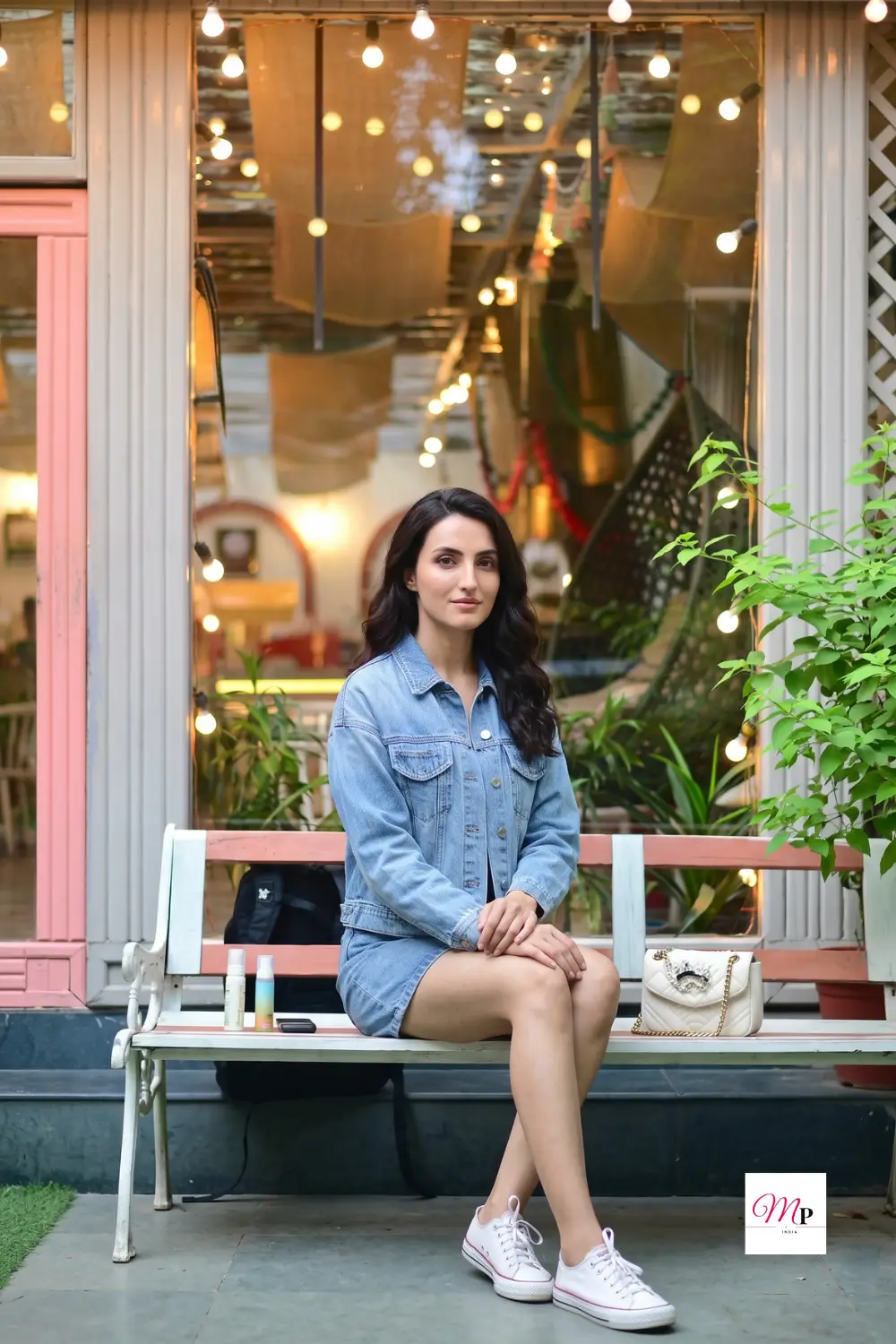 Women denim jacket India styled for evening cafe outing with string lights and casual white sneakers