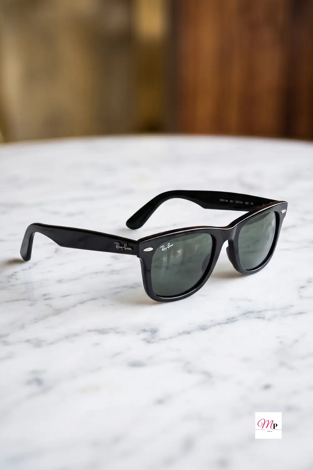 Kaale frame waale Ray-Ban sunglasses on white marble surface with warm wood background studio shot