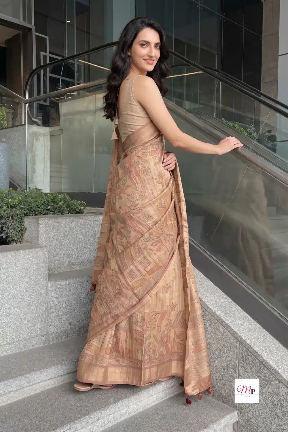 Back view of warli art silk blend saree showing pallu drape and pleat structure on granite stairs