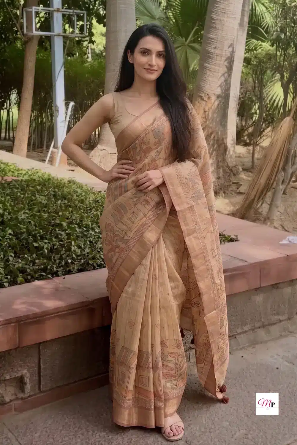 Beige handloom style saree with warli motifs styled for outdoor occasion in garden setting full length view