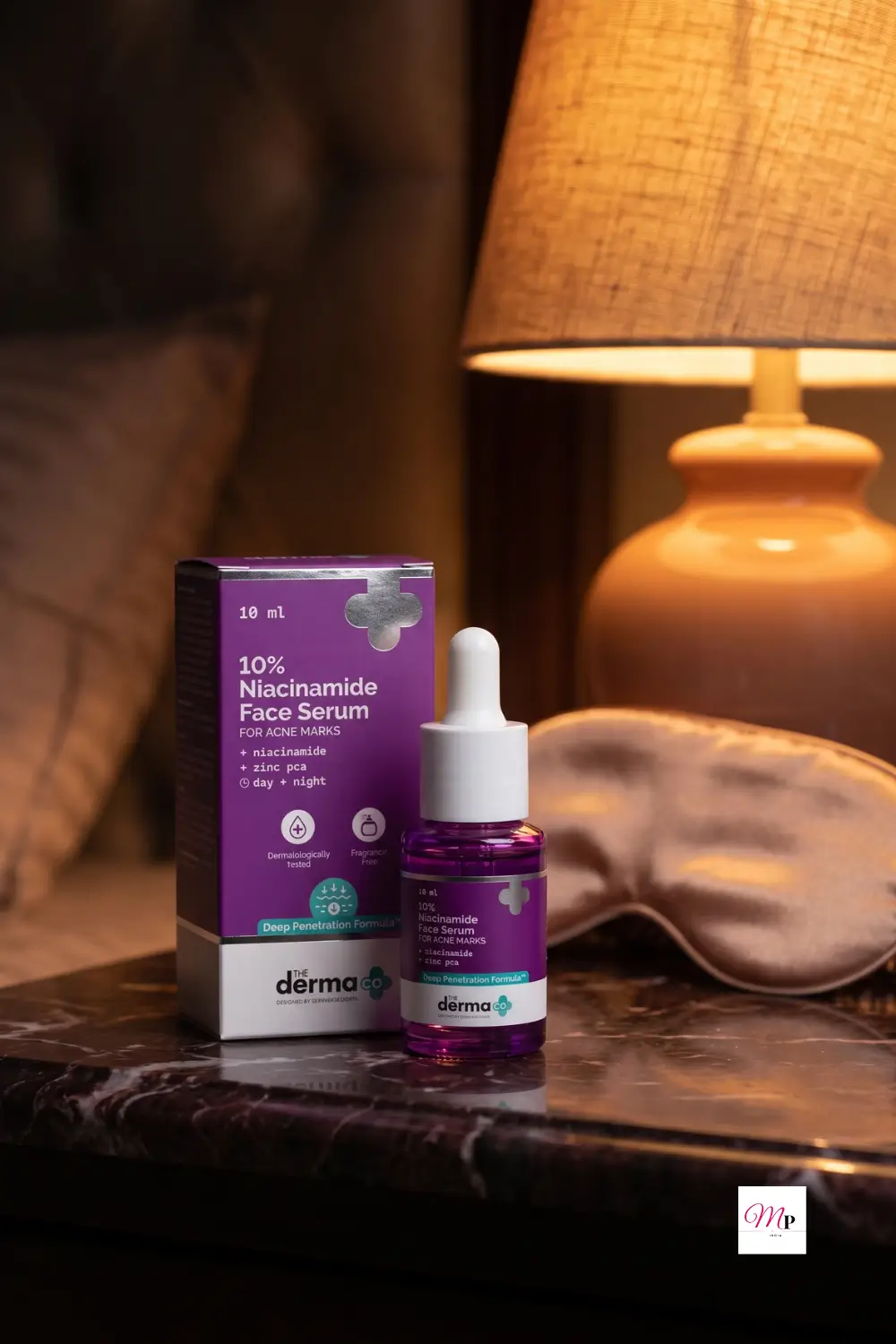The Derma Co 10% Niacinamide Serum on dark marble bedside table with warm lamp glow