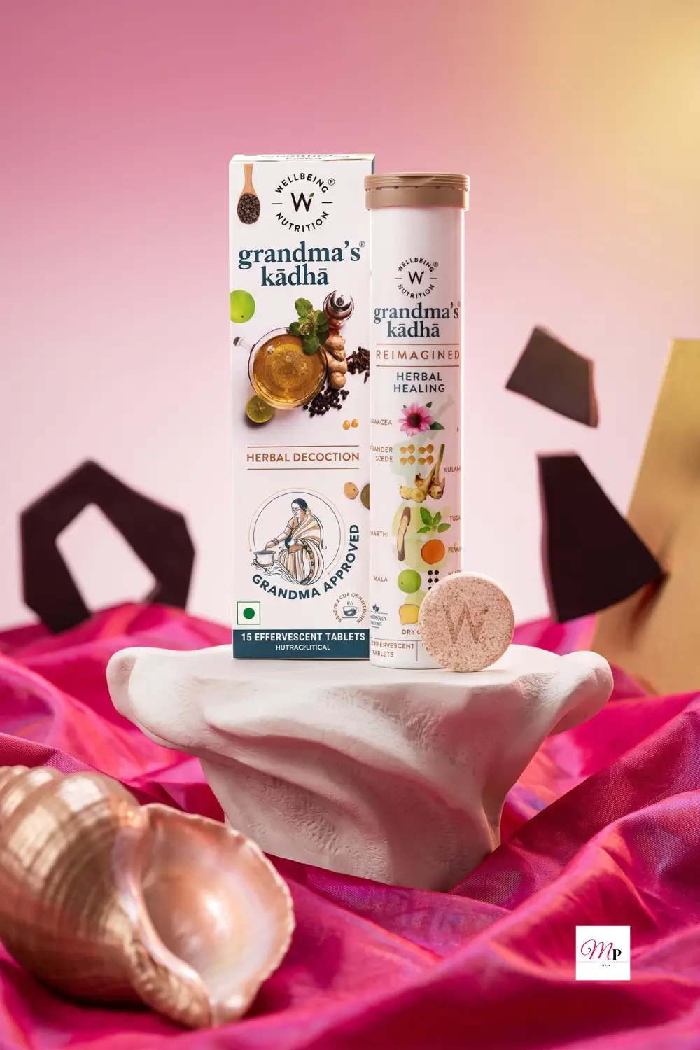 Wellbeing Nutrition Grandma's Kadha ayurvedic immunity booster effervescent tablets with box and tube on a sculptural pedestal with pink silk fabric