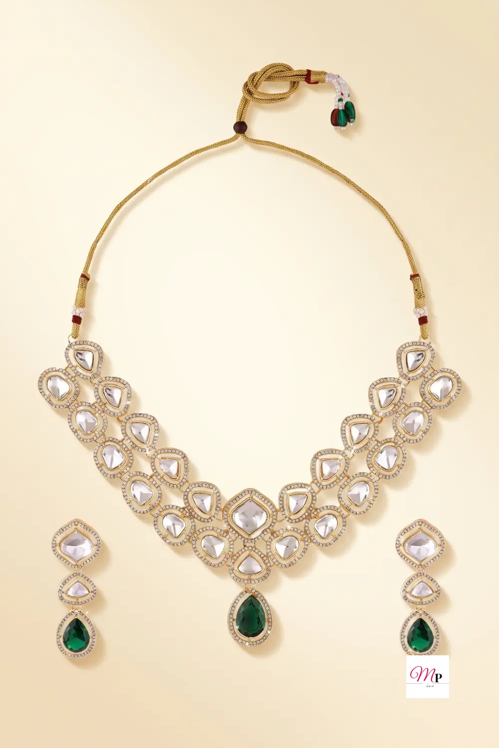 Gold plated kundan necklace and earrings set with white and green stones on cream background