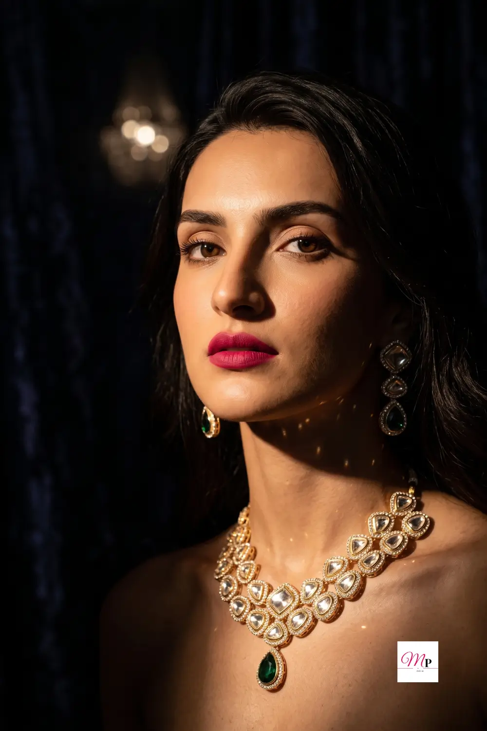 Model wearing traditional gold plated necklace set with emerald drops in dramatic evening lighting