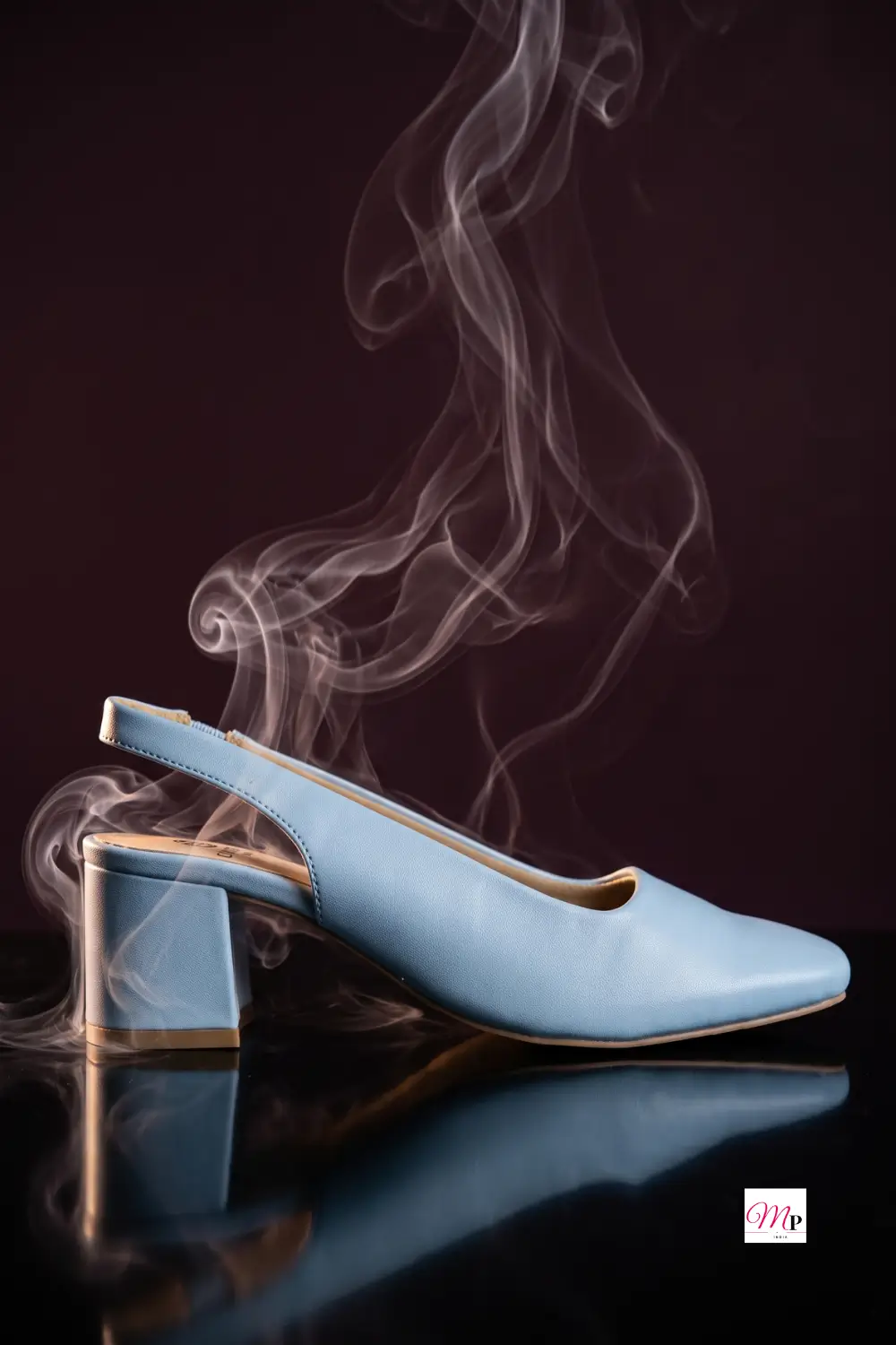 Ice blue block heel on reflective black surface with smoke wisps