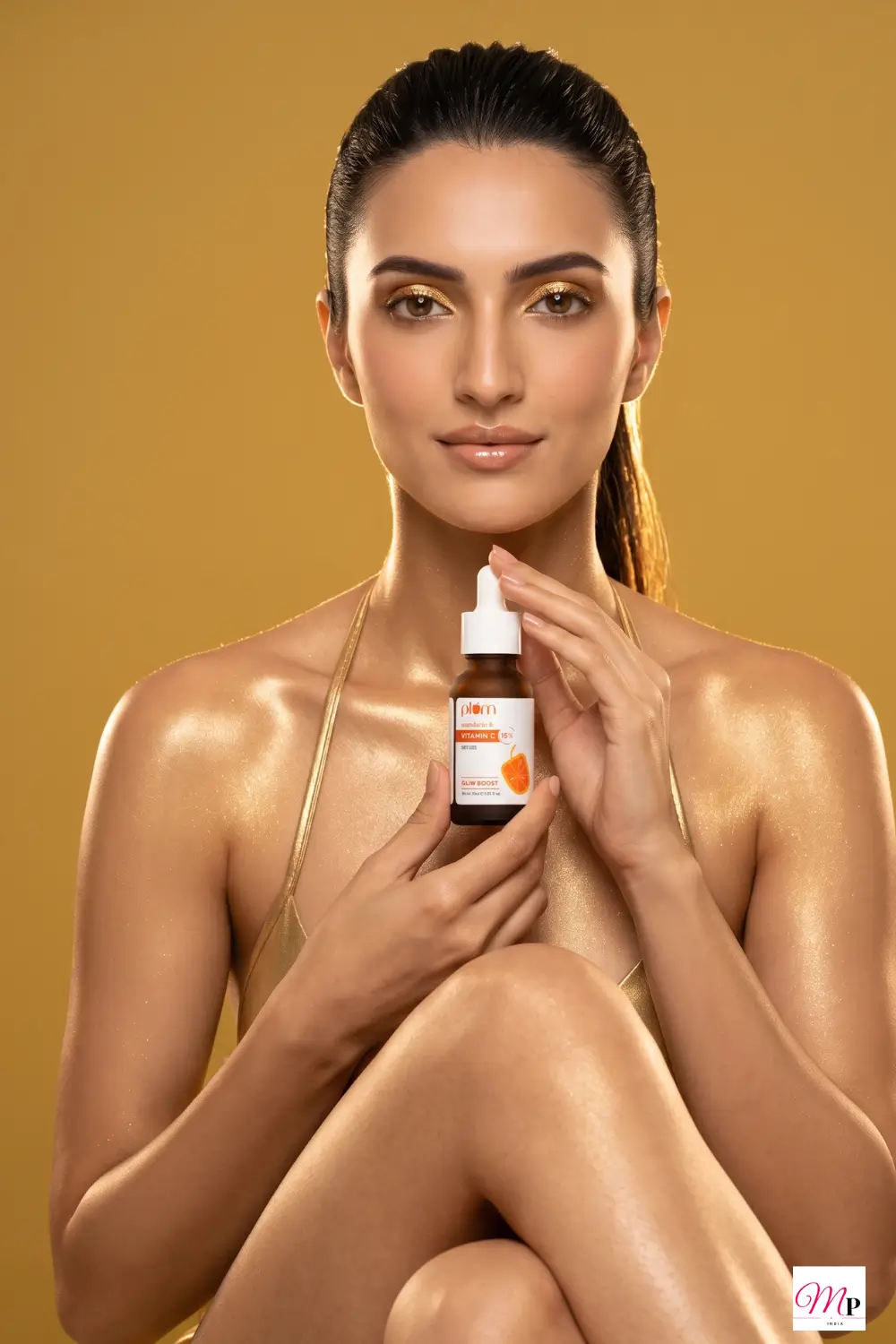 Model with luminous highlighted skin holding Plum 15% Vitamin C serum against warm golden background — vitamin c serum for pigmentation