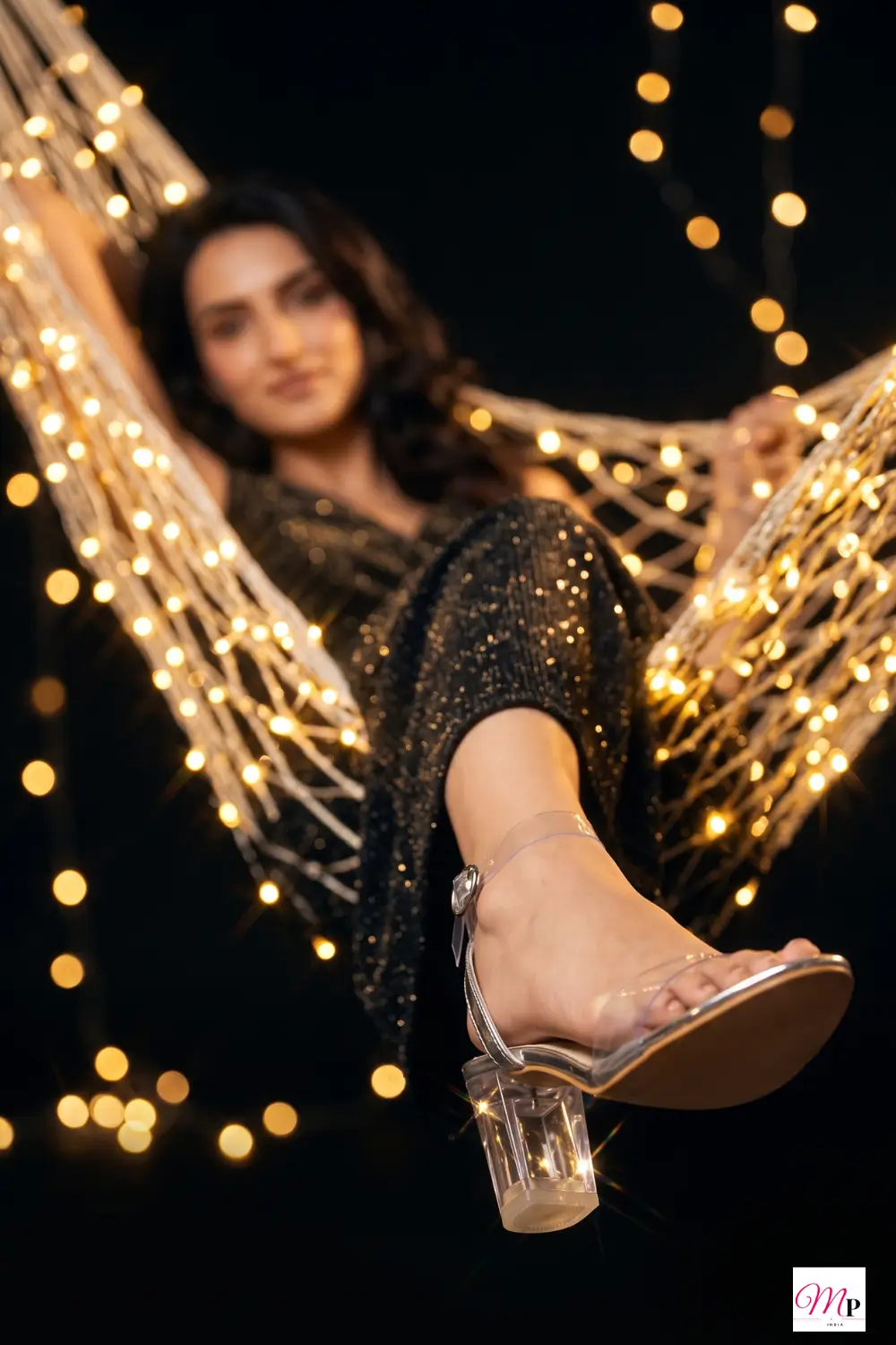 woman dancing in transparent block heels with fairy lights at festive sangeet night
