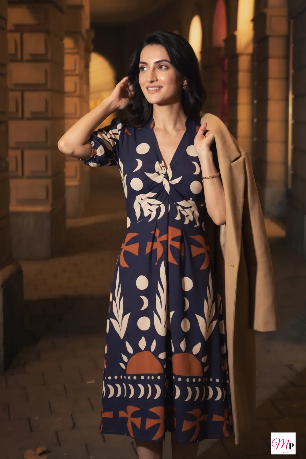 Crepe midi dress styled with a camel coat draped over the arm for an evening dinner look