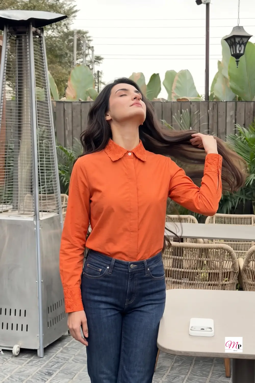 Rust orange formal shirt for office women showing drape and movement, terrace hair-flip shot